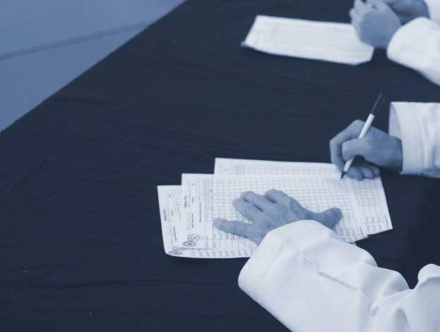 instructor writing on paper grading student performance