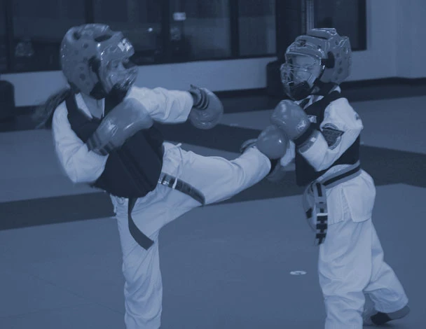a kid kicking towards another kid in a taekwondo sparring match